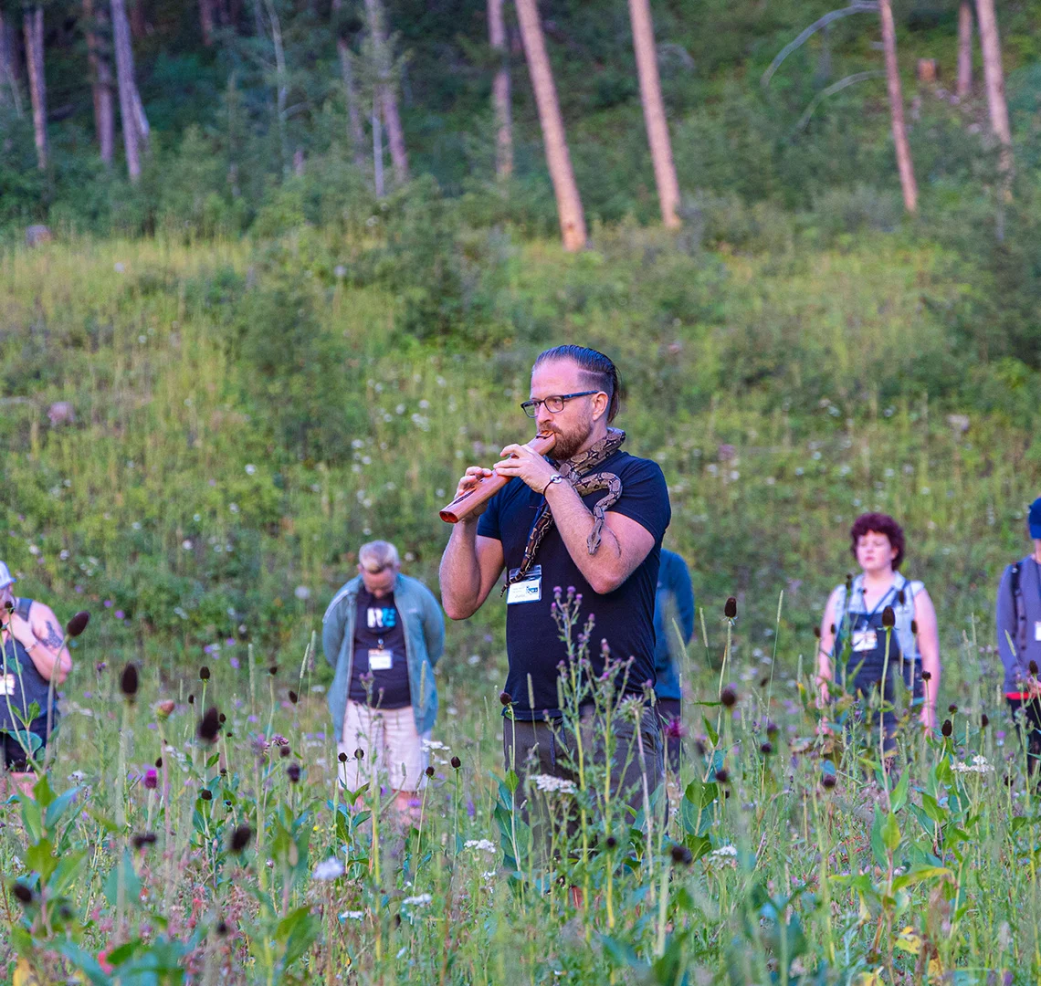 Justin playing flute in a meadow